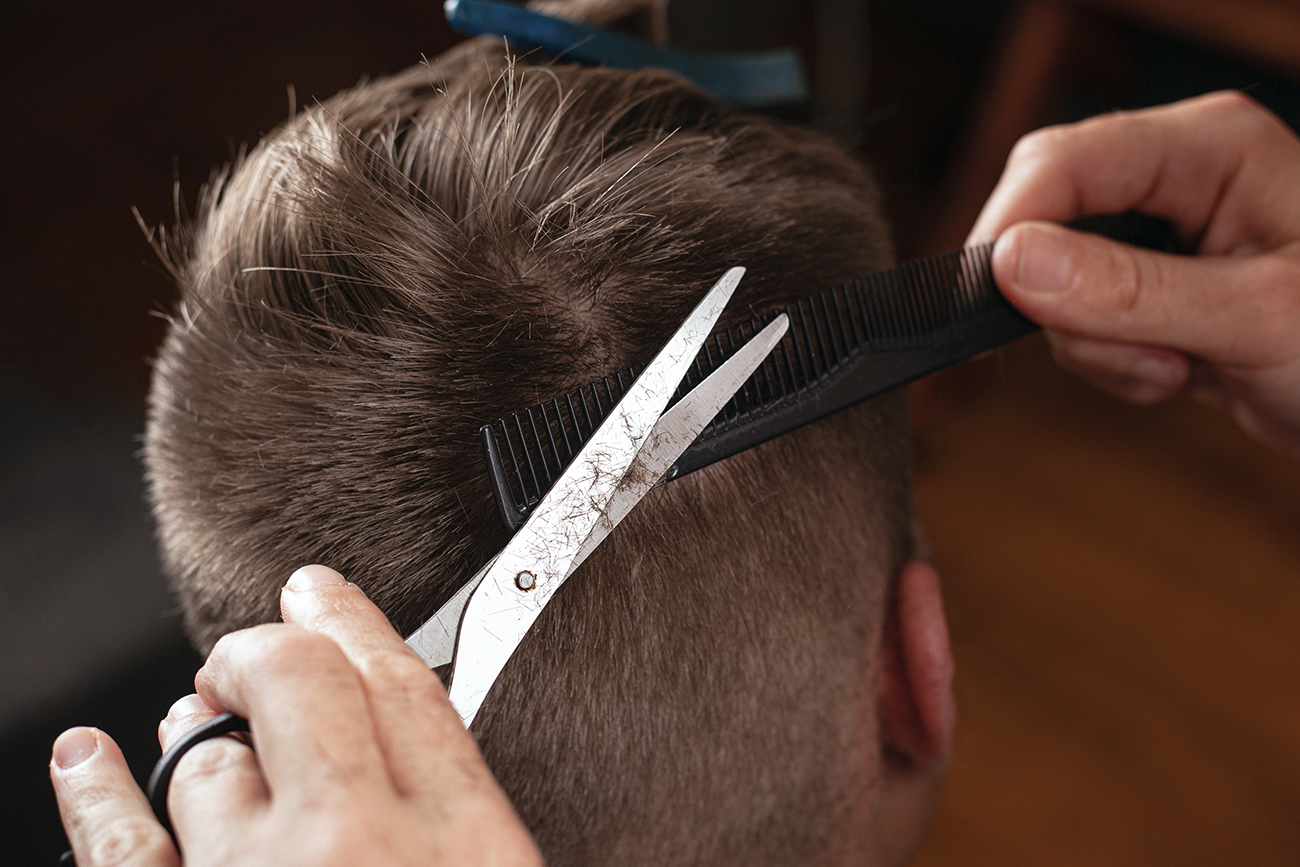 barber cut man's hair, modern haircut with scissors.