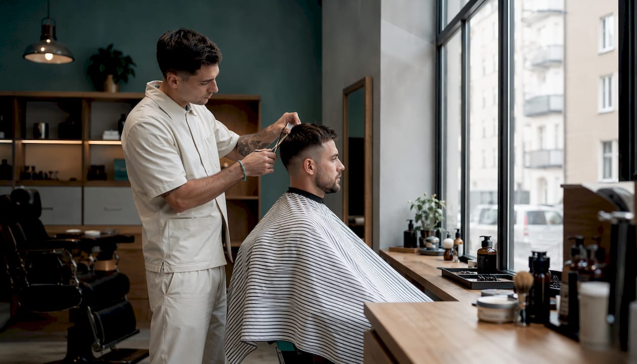 Chlap si necháva upraviť vlasy v barbershope.