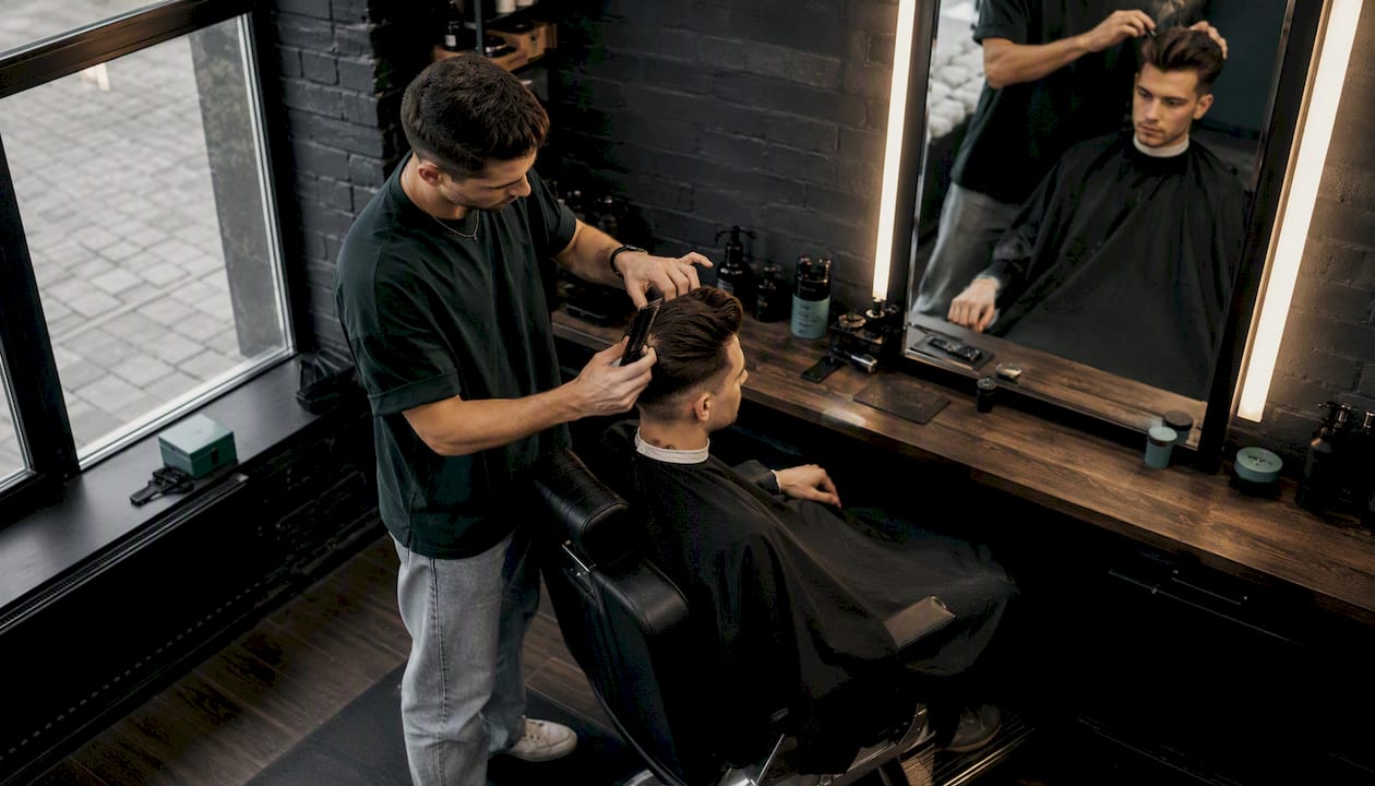 Barber práve dolaďuje moderný quiff-pompadour účes.