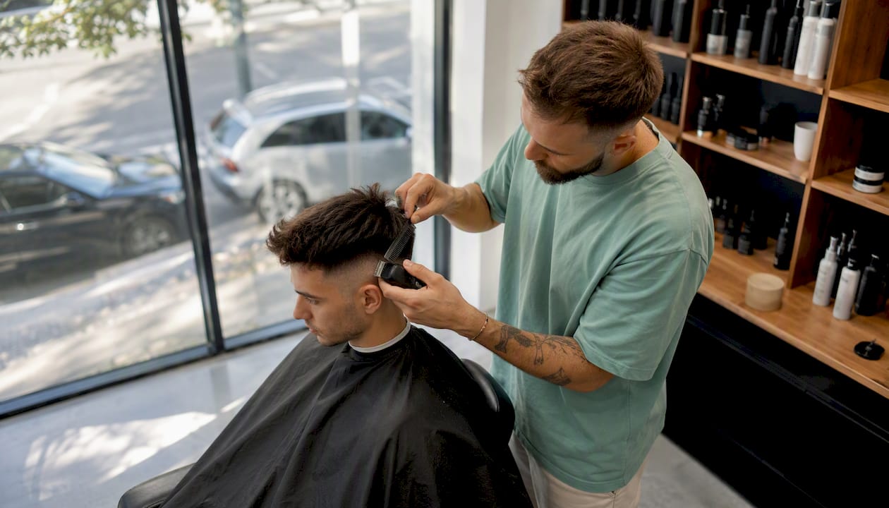Mladý muž si dáva v barbershope ostrihať vlasy na moderný high fade.