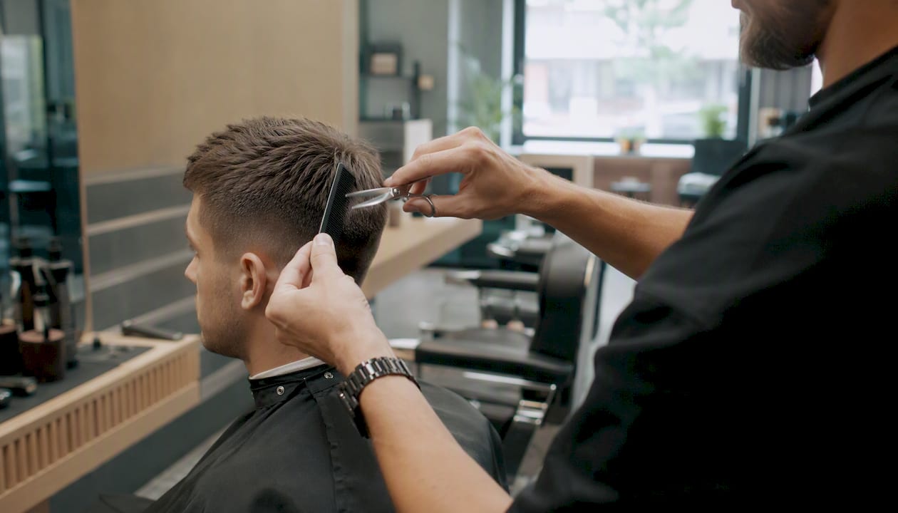 Barber upravuje krátky pánsky účes.